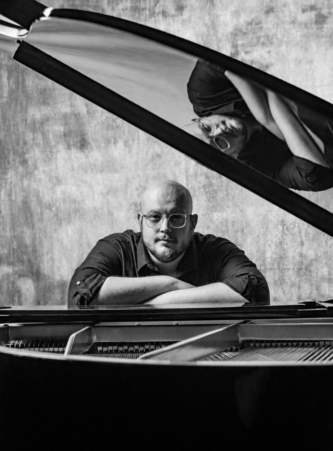 Jeffrey Carabelos leaning on a grand piano in the studio
